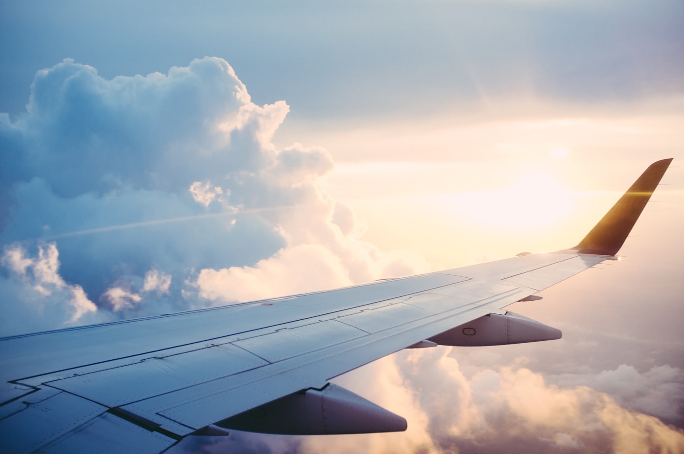 An aeroplane wing above the clouds at sunset